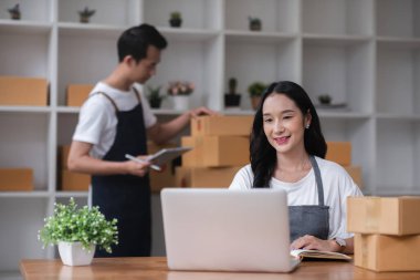 Bir çift online satıcı online siparişleri almak ve müşterilere teslimat için ürünleri paketlemek için birlikte çalışır...