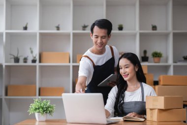 Bir çift online satıcı online siparişleri almak ve müşterilere teslimat için ürünleri paketlemek için birlikte çalışır...