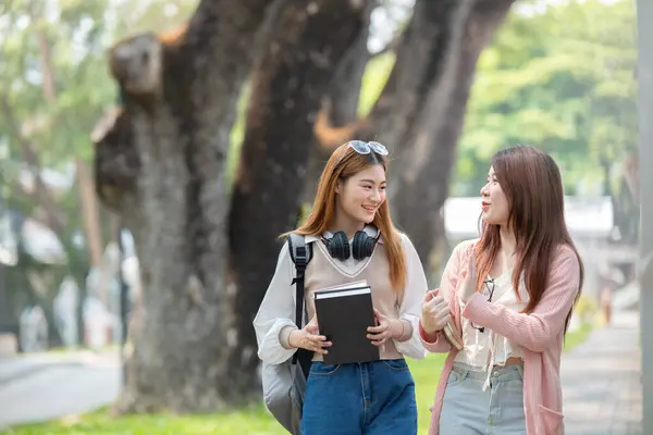 Two female student friends were chatting while walking to a classroom on campus..