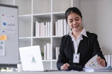 Finans belgeleriyle oturan muhasebeci, dizüstü bilgisayar kullanan, ofisteki şirket için mali ve vergi rakamlarını hesaplayan..