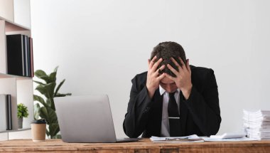 İş adamı, dizüstü bilgisayarı, stres ve tükenmişlik kavramını masasında hayal kırıklığı içinde tutuyor..