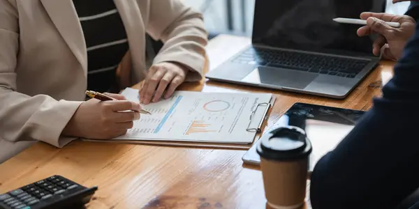 stock image Business professionals reviewing financial reports and using laptop, concept of teamwork and financial planning.