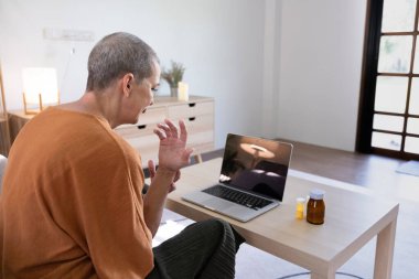 Elderly woman using a laptop for a virtual health consultation, demonstrating proactive health management and the use of modern technology. clipart