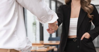 Modern bir ofiste el sıkışan iki iş adamı, başarılı bir ortaklığı ve anlaşmayı simgeliyor..