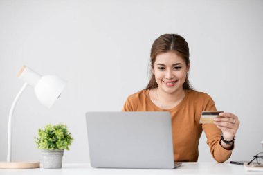 İnternetten alışveriş yapan ve kredi kartıyla ödeme yapan bir kadın, evden gelen e-ticaretin rahatlığıyla eğleniyor..