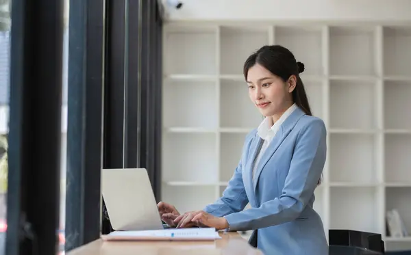 stock image Business woman working on a laptop in a modern office, focused and productive, wearing formal attire.