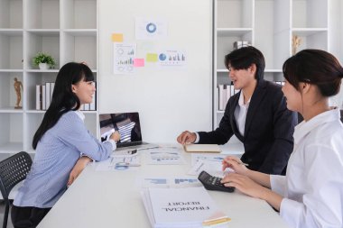 Profesyonel muhasebecilerden oluşan bir ekip, finansal hesaplama ve raporları, dizüstü bilgisayarları ve yazılı belgeleri değerlendirmek üzere modern bir ofiste toplandı..