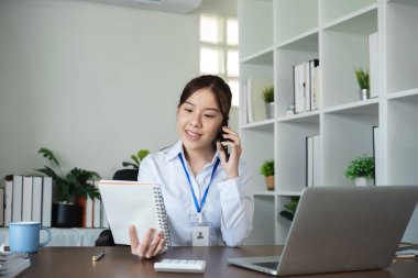 Modern bir ofiste çalışan, bilgisayarla, belgelerle ve telefonla konuşan bir kadın muhasebeci..