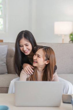 Lezbiyen çift sıcak bir oturma odasında birlikte oturup, keyifli bir anı paylaşıyorlar. Aşk, çeşitlilik ve modern LGBT yaşam tarzı temaları için mükemmel..