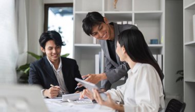 Modern ofis ortamında bir toplantı sırasında iş birliği yapan ve fikir alışverişinde bulunan iş adamları.