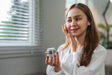 Sabahları makyaj yapan güzel bir kadın modern bir evde doğal ışıkla eğleniyor..