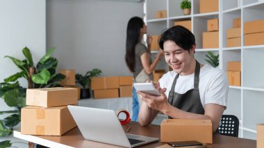 Kutu paketlemek ve online satış işlerini modern bir ofisten yönetmek için çalışan genç bir çift..