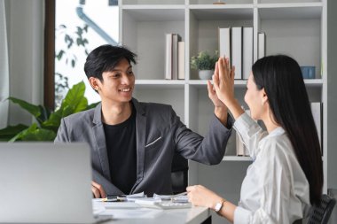 Modern bir ofiste iki profesyonel beşlik çakıyor başarılı bir toplantı ve takım çalışmasını kutluyorlar..