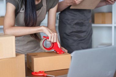 Ofislerinde birlikte çalışan bir çift online e-ticaret işleri için sipariş alıyor ve ürün paketliyorlar..