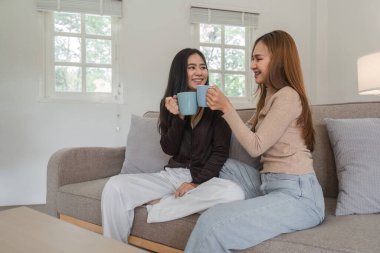 Sevgi dolu lezbiyen bir çift, modern oturma odasındaki rahat bir kanepede kahvelerini yudumluyor..