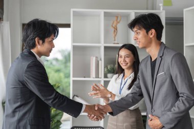 Modern bir ofiste çeşitli bir iş ekibi, el sıkışıyor ve başarıyı kutluyor, takım çalışması ve profesyonel işbirliği sergiliyor..