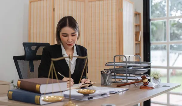 stock image A female lawyer in a modern office examines contract documents related to a lawsuit, showcasing professionalism and legal expertise.