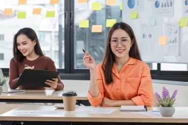 Modern bir ofiste çalışan genç bir iş kadını, iş arkadaşları ve yaratıcı çalışma alanlarıyla çevrili, üretkenliği ve işbirliğini teşvik ediyor..