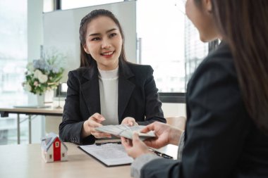 Modern bir ofiste profesyonel gayrimenkul acenteleri ev alıp satmak için sözleşmeleri ve işlemleri tartışıyorlar..