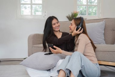 Neşeli bir LGBT lezbiyen çifti sıcak, modern bir oturma odasında bir anlık mutluluğu paylaşıyor..