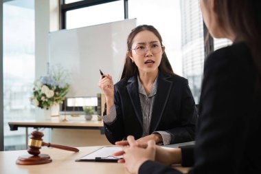 Profesyonel kadın avukat hukuki konuları tartışıyor ve bir müşteriye çağdaş ofis ortamında danışmanlık yapıyor..