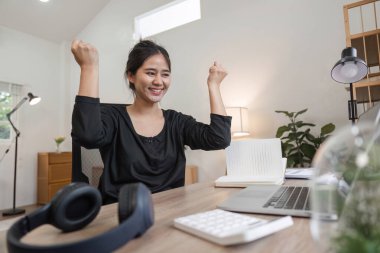 Evden çalışan genç bir kadın muhasebeci modern ofis düzeninde başarılı bir başarıyı kutluyor..