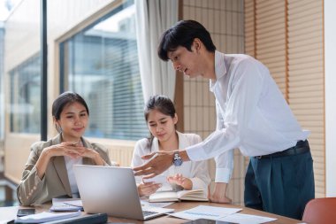 Çağdaş bir ofis ortamında fikirleri tartışan ve paylaşan bir grup iş adamı, takım çalışmasını ve işbirliğini teşvik ediyor.