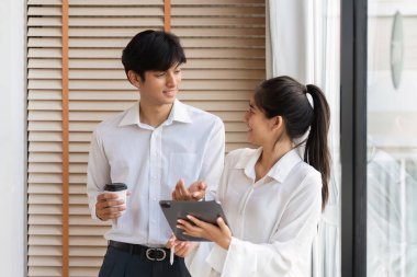 Modern ofis ortamındaki iki iş adamı, bir tartışma ve fikir alışverişinde bulunuyorlar, işbirliği ve takım çalışmasını teşvik ediyorlar..