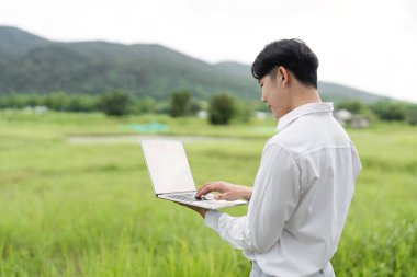 Tarımsal verileri toplamak ve analiz etmek için dizüstü bilgisayar kullanan bir araştırmacı, modern tarım uygulamalarında teknolojinin entegrasyonunu gösteriyor.