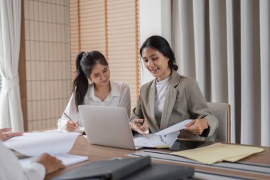 Modern bir ofis ortamında iş projelerini tartışan ve danışmanlık yapan profesyonel iş ekibi, takım çalışması ve işbirliği sergiliyor..