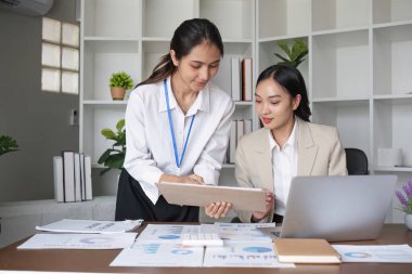 Modern ofis ortamında birlikte çalışan iki genç kadın muhasebeci takım çalışması ve profesyonellik sergilediler..