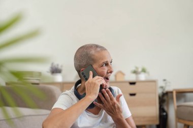 Elderly woman using a smartphone to communicate, showcasing modern technology in a home setting. clipart