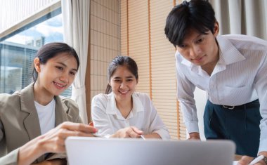 Modern bir ofiste iş birliği yapan ve fikir alışverişinde bulunan üç iş adamı, yenilik ve takım çalışmasını teşvik ediyor..