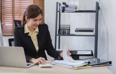 Modern bir ofiste dizüstü bilgisayar kullanan profesyonel bir iş kadını kendini adamışlık ve verimlilik sergiliyor..