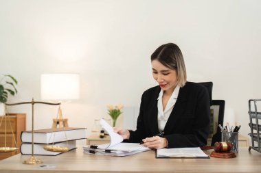 Modern bir ofiste kadın bir avukat davayla ilgili sözleşme belgelerini inceliyor, profesyonellik ve hukuki uzmanlık gösteriyor..