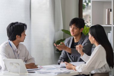 Modern bir konferans odasında fikir alışverişinde bulunan bir grup iş adamı takım çalışması ve işbirliği sergiliyor..