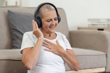 Yaşlı bir kadın, rahat bir oturma odasında kulaklıkla müzik dinlerken bir anlık rahatlıktan zevk alır..