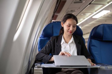 Uçuş sırasında dizüstü bilgisayarda çalışan genç bir muhasebeci, modern uzaktan çalışma esnekliği ve profesyonel adanmışlığı sergiliyor..