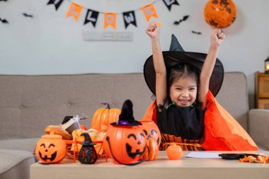 Cadı kostümü giymiş sevimli bir genç kız. Cadılar Bayramı şenliklerinin tadını çıkarıyor. Balkabakları ve garip dekorasyonlarla..