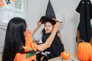 Bir anne ve kız Cadılar Bayramı aktivitelerine katılır, kostüm giyer ve evdeki şenlikli dekorasyonların tadını çıkarırlar..