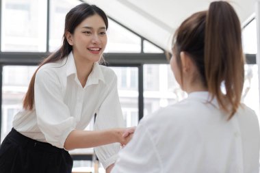 İki kadın muhasebeci, parlak ve modern ofis ortamında finansal belgeler üzerinde tartışır ve çalışır..