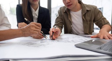 Proje planları üzerinde birlikte çalışan, stratejileri tartışan ve modern ofis ortamında kararlar alan odaklanmış iş adamları..