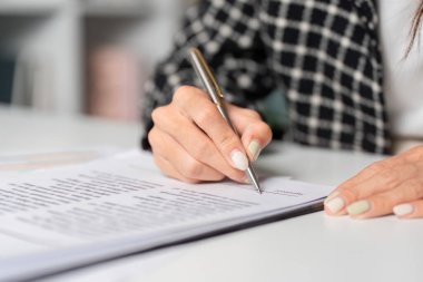 İş adamının ofis masasında kalemle kontrat imzalaması profesyonel bir iş anlaşmasını sembolize ediyor..