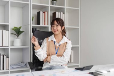 Modern ofis ortamında masasında otururken kendine güvenen çekici genç bir ofis çalışanı..