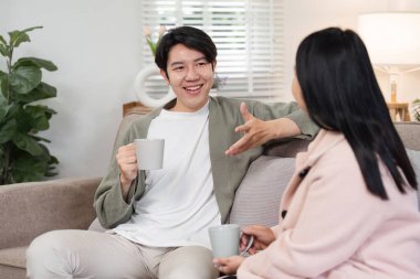 Bir anne ve oğlu sıcak bir oturma odasında, sıcak içeceklerin tadını çıkararak ve sohbet ederek rahatlatıcı bir anı paylaşıyorlar..