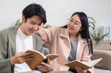 Bir anne ve oğlu modern bir oturma odasında birlikte rahatlar, kitap okur ve kaliteli zaman geçirirler..