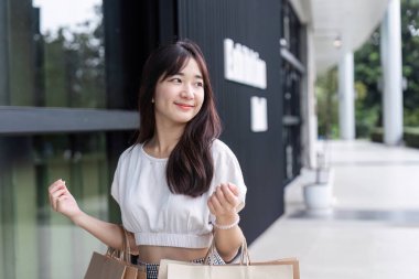 Şık bir alışveriş merkezinde alışveriş torbaları tutan sevimli bir kız perakende terapi ve modern moda zevkini yakalıyor..