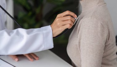 Modern bir klinik ortamında tıbbi muayene sırasında bir hastaya danışmanlık yapan bir doktor.