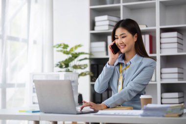 Modern ofis ortamında çalışan bir kadın muhasebeci, dizüstü bilgisayarını kullanan bir müşteriyle bağlantı kurar..