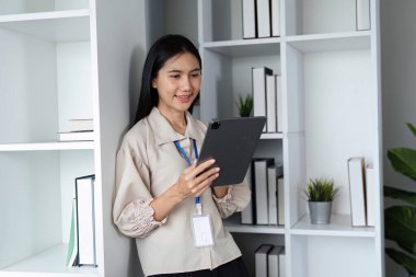 Modern bir ofiste tablet üzerinde çalışan kararlı bir iş kadını profesyonelliği ve odaklanmayı gösteriyor..